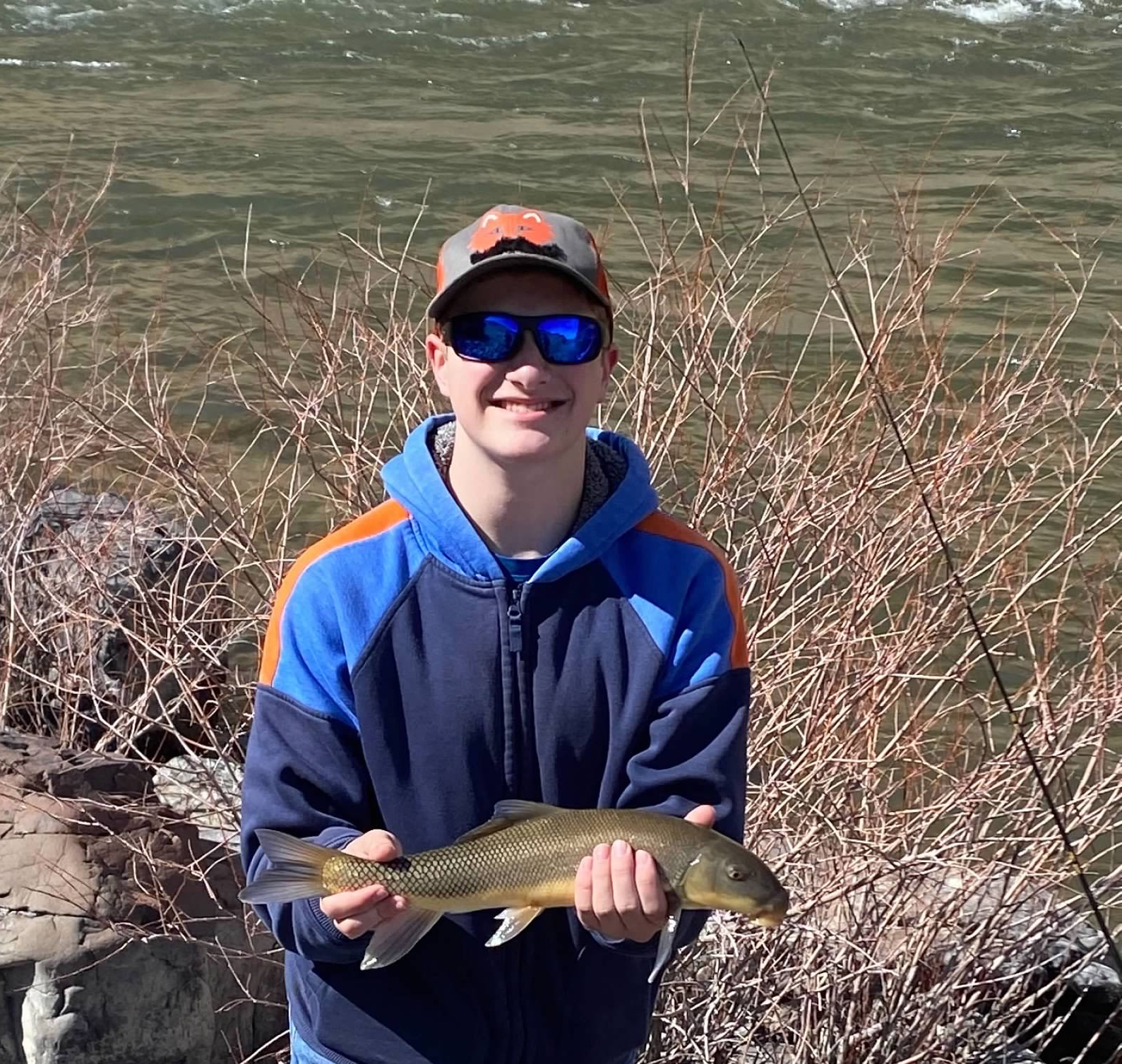 Bryan holding a fish by a river.